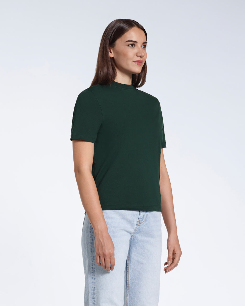 A woman at an angle with her arms at her sides, modelling a plain green short sleeve organic cotton t shirt.