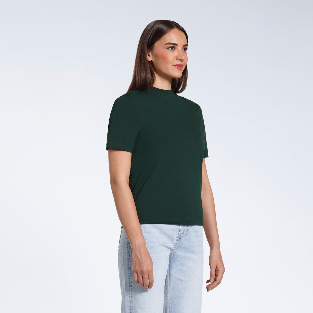 A woman at an angle with her arms at her sides, modelling a plain green short sleeve organic cotton t shirt.