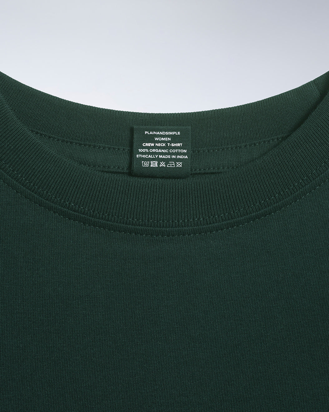 A close up of an neck label in a women's green short sleeve crew neck organic cotton t shirt.