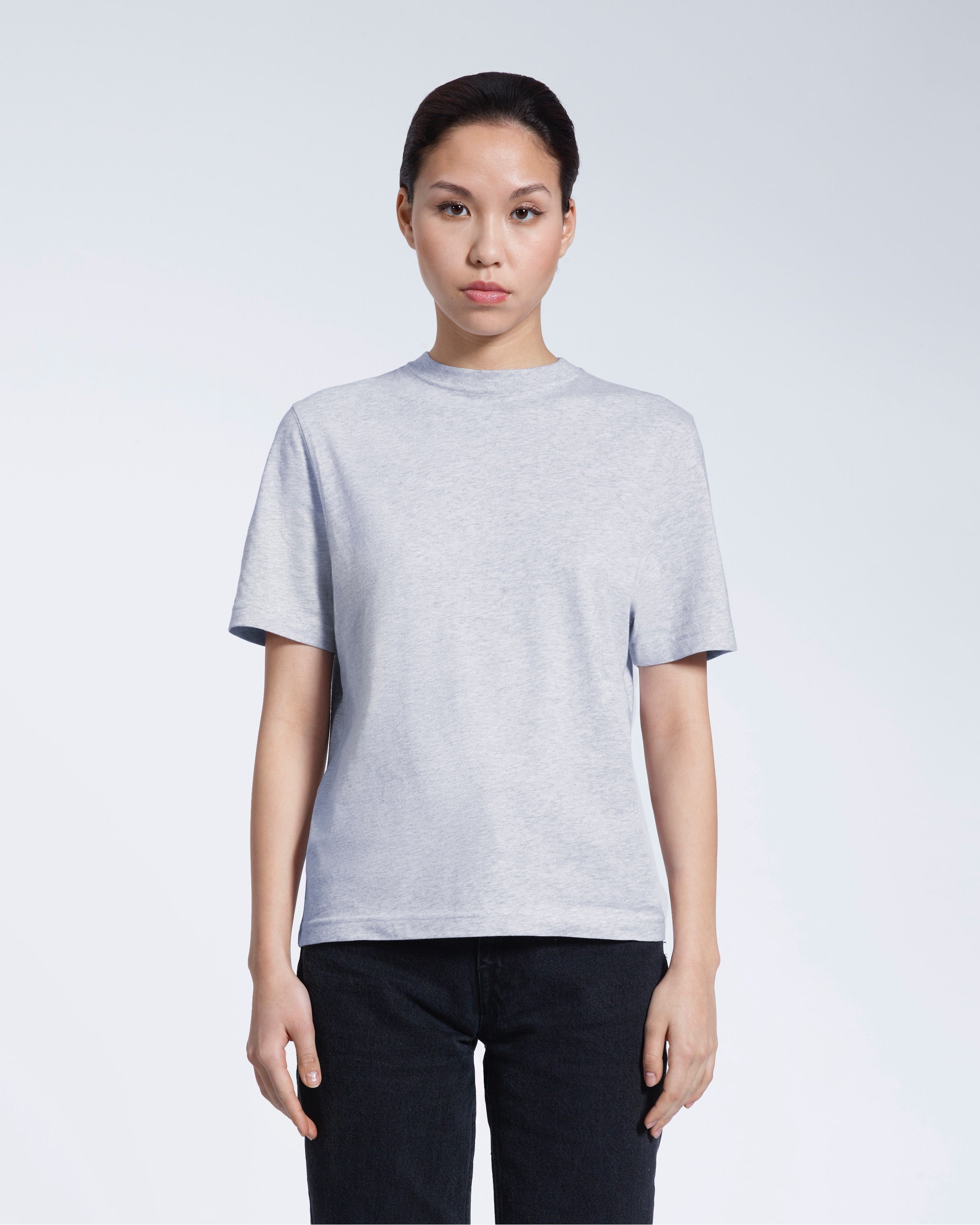 A woman facing front on looking at the camera, modelling a grey short sleeve organic cotton t shirt.