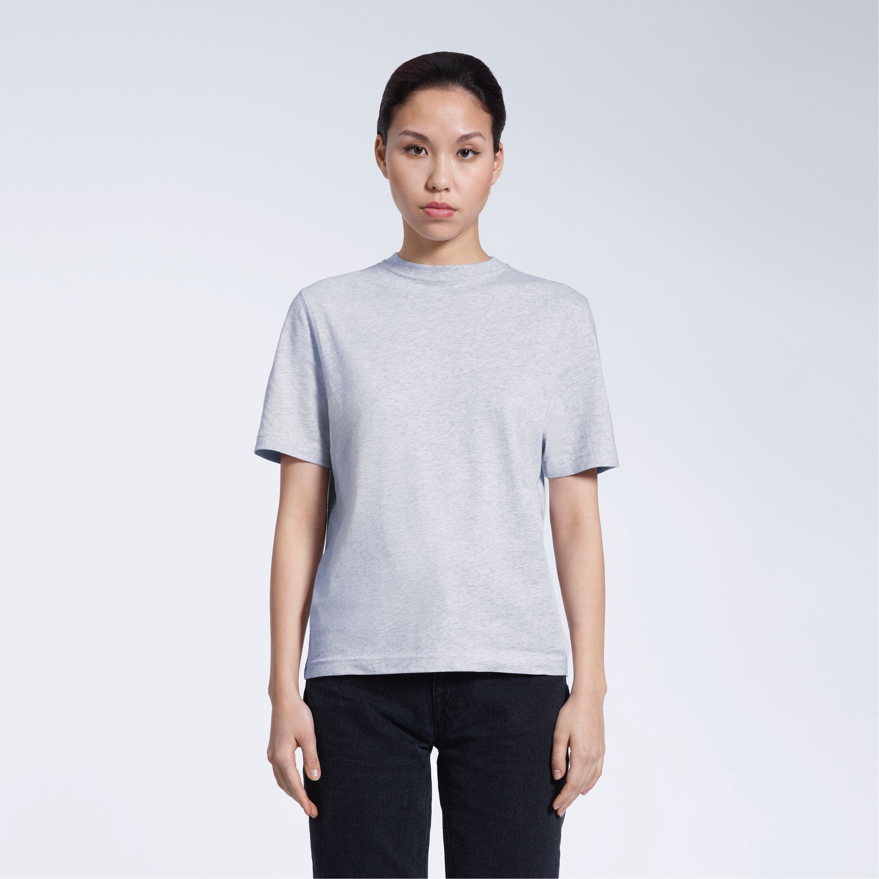 A woman facing front on looking at the camera, modelling a grey short sleeve organic cotton t shirt.