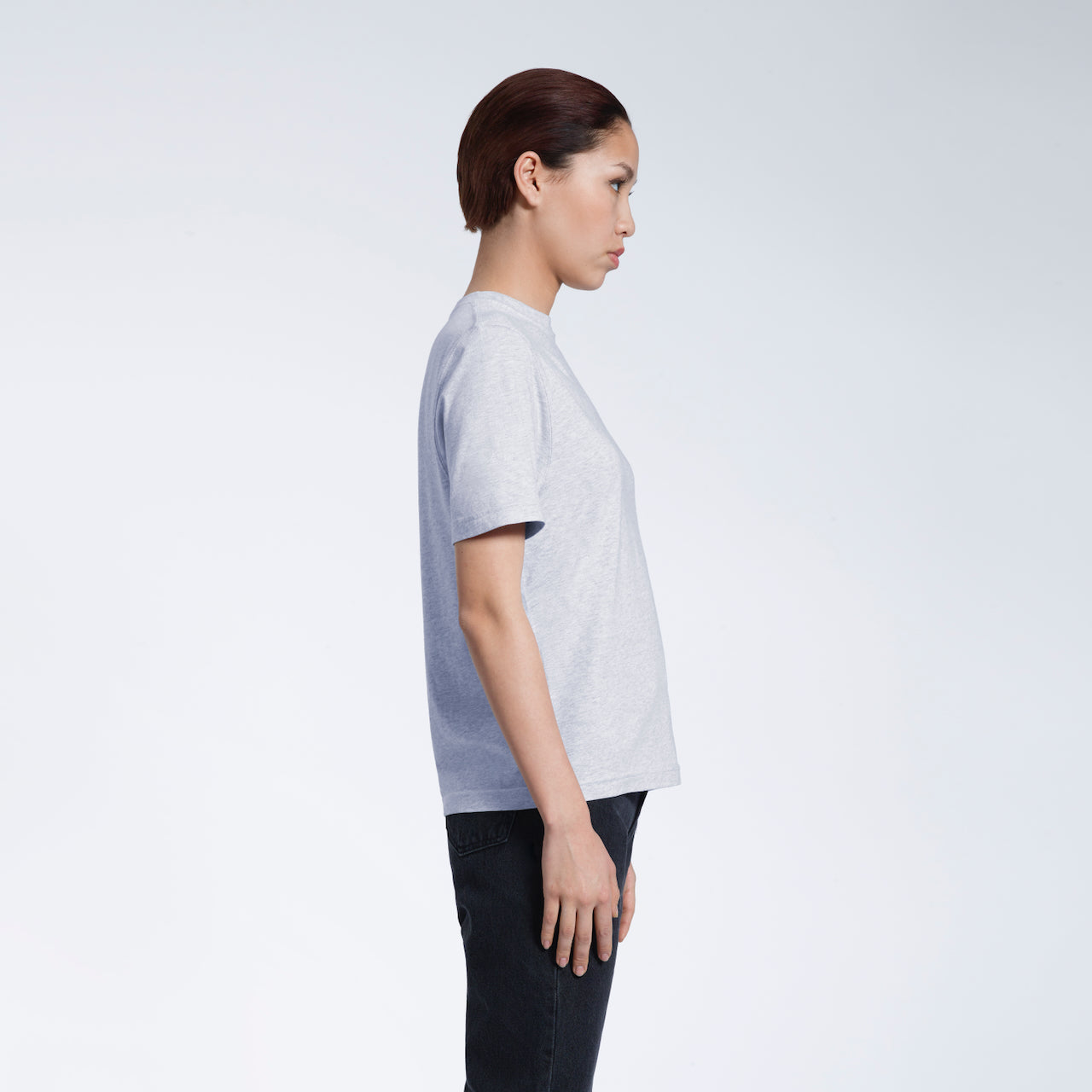A woman facing side on, modelling a plain grey coloured short sleeve organic cotton t shirt.