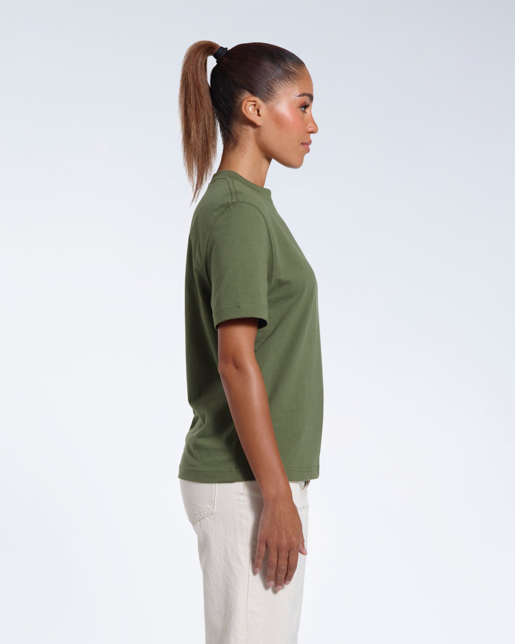 A woman facing side on, modelling a plain khaki green short sleeve organic cotton t shirt.