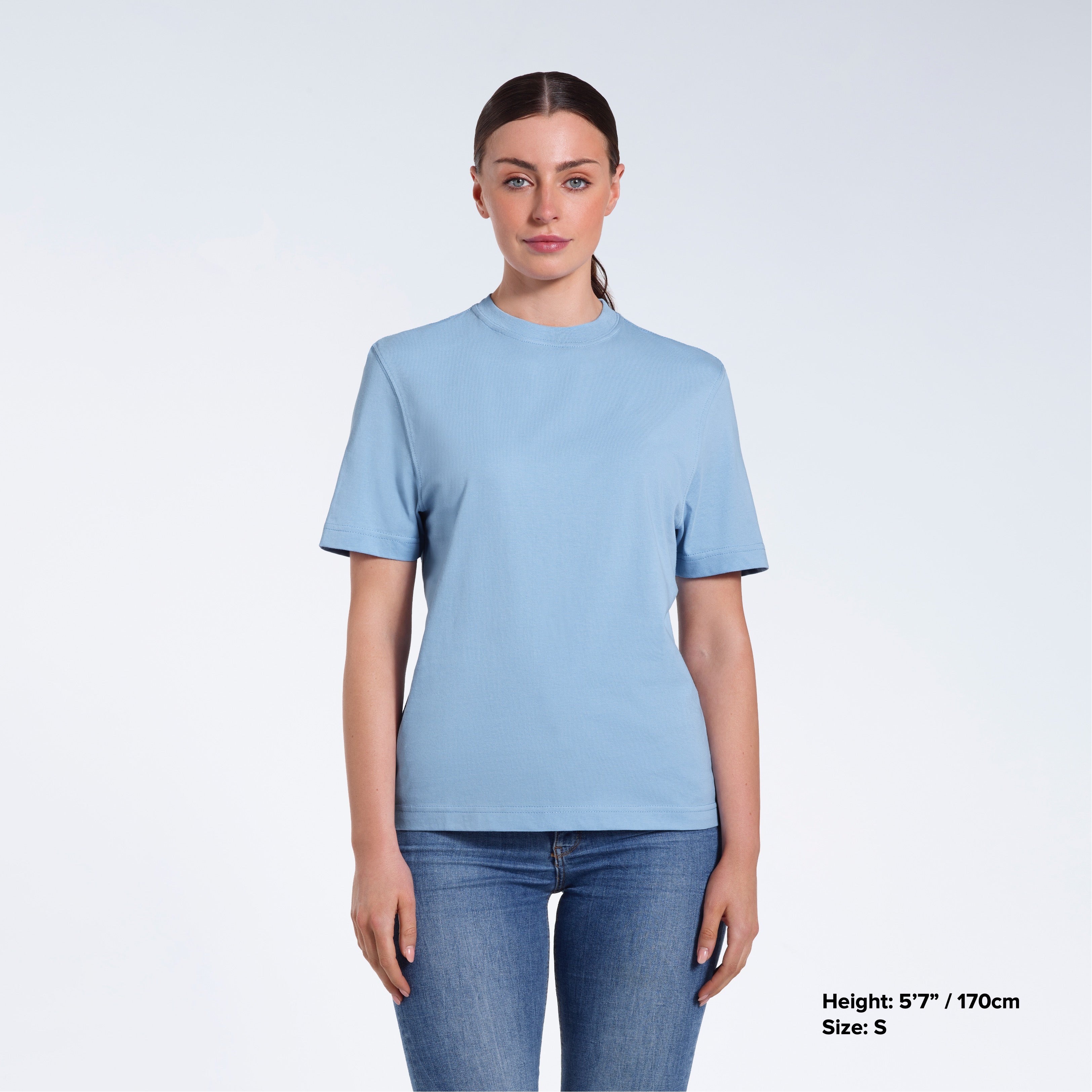 A woman facing front on looking at the camera, modelling a blue short sleeve organic cotton t shirt.