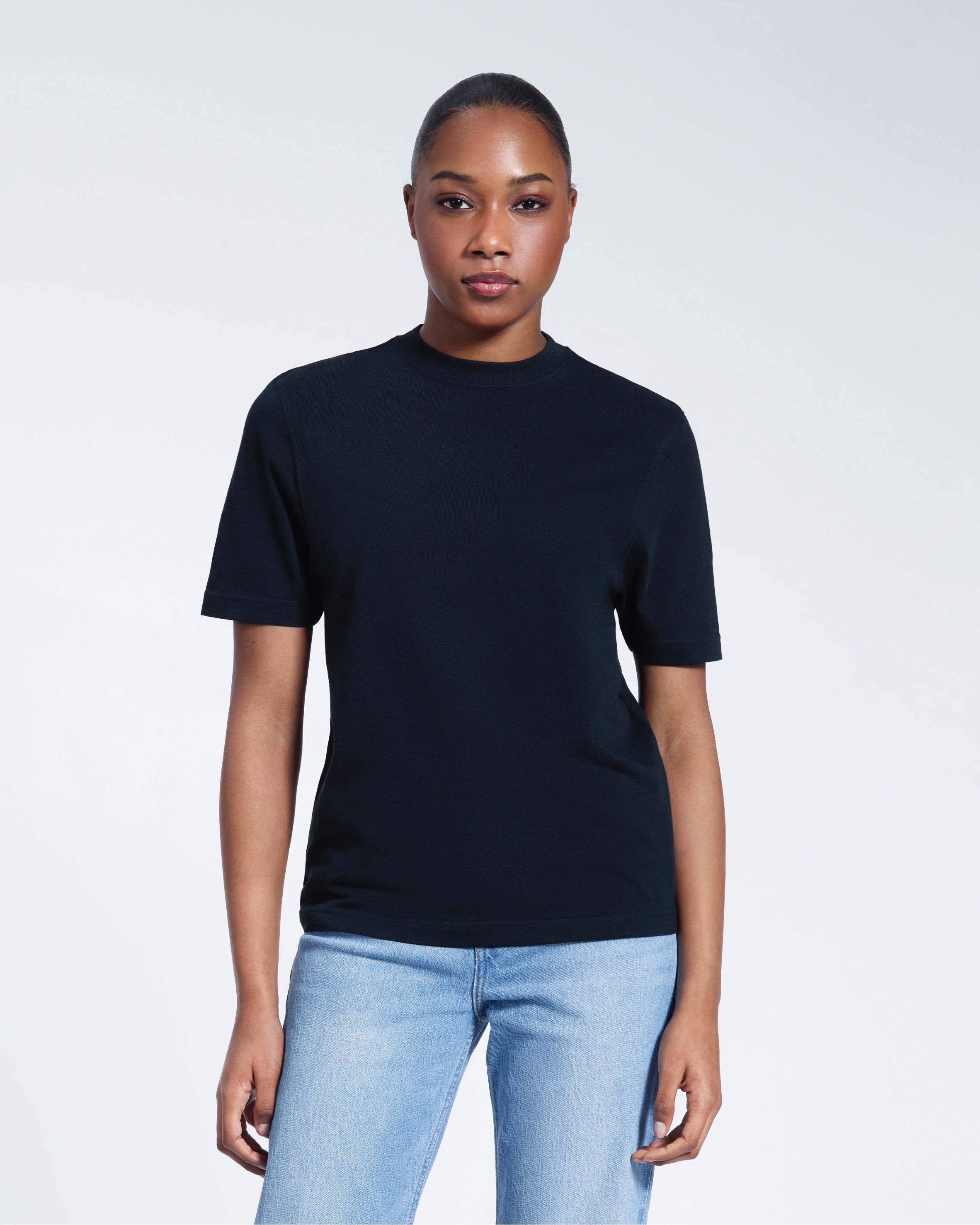 A woman facing front on looking at the camera, modelling a navy short sleeve organic cotton t shirt.