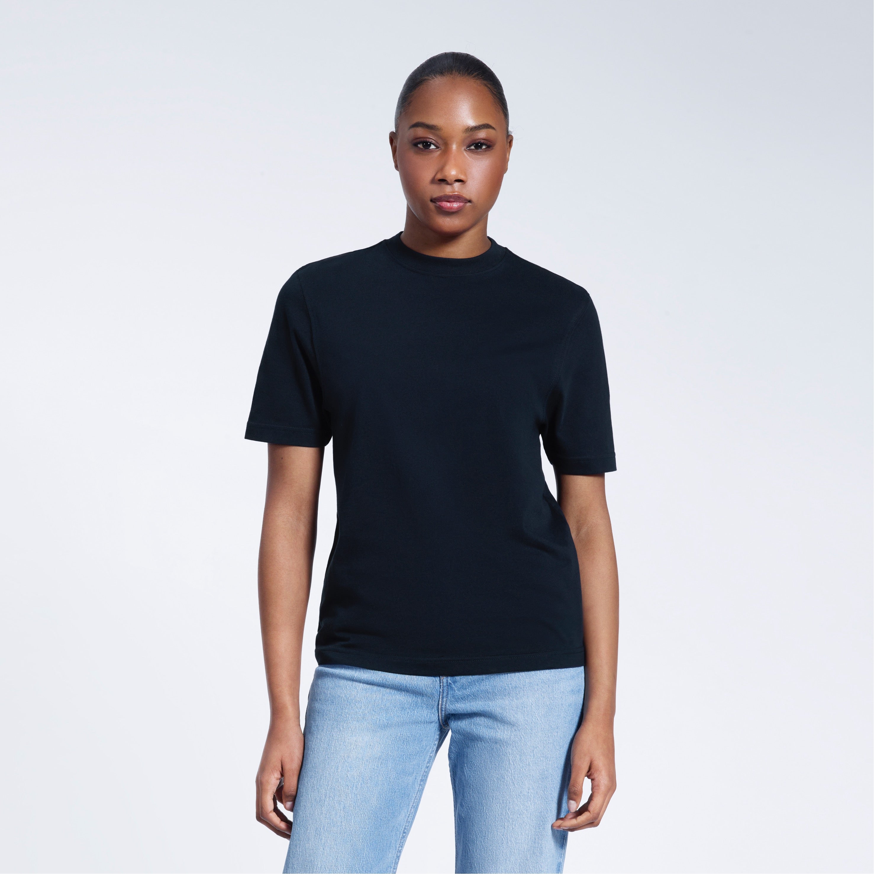 A woman facing front on looking at the camera, modelling a navy short sleeve organic cotton t shirt.