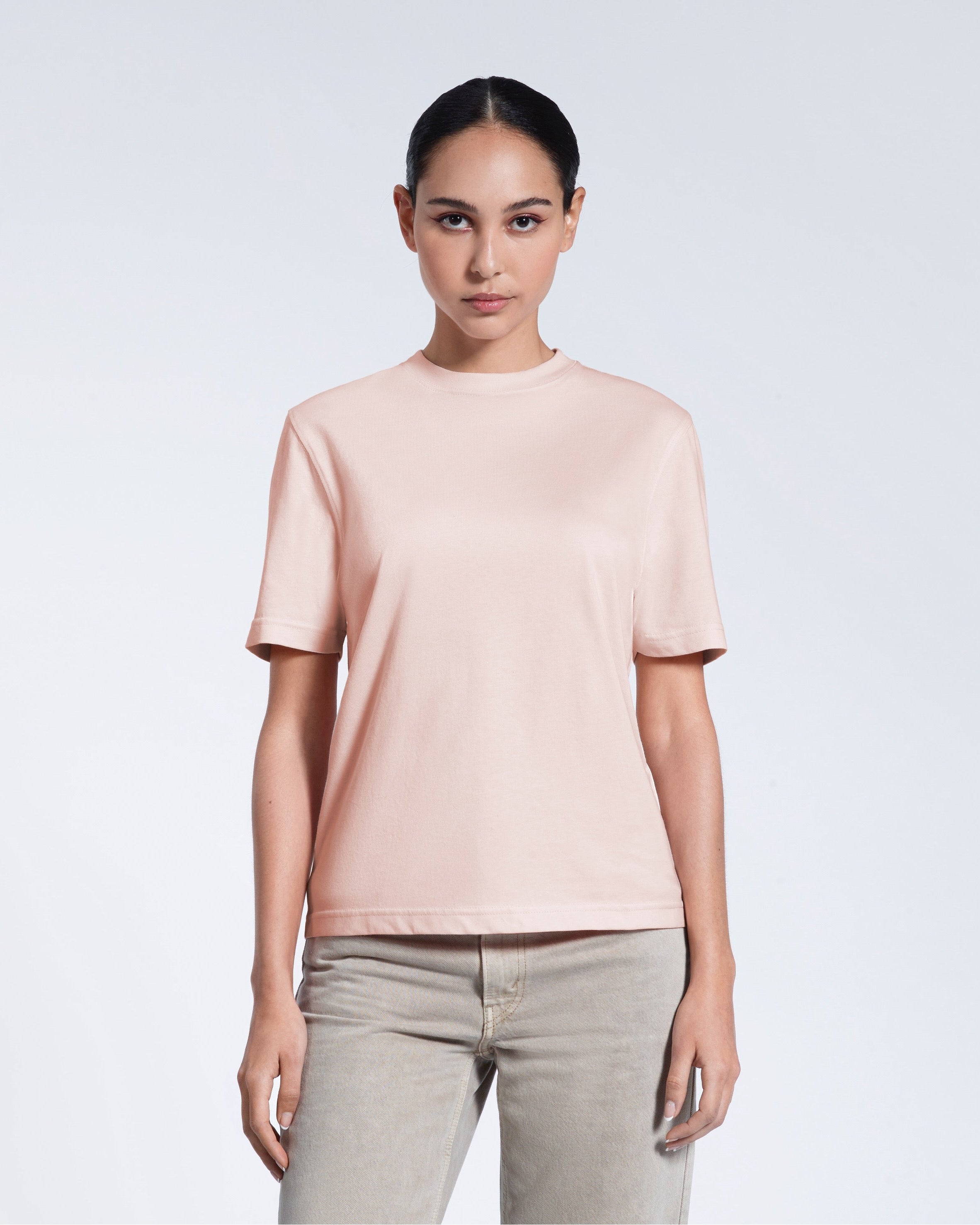 A woman facing front on looking at the camera, modelling a pink short sleeve organic cotton t shirt.