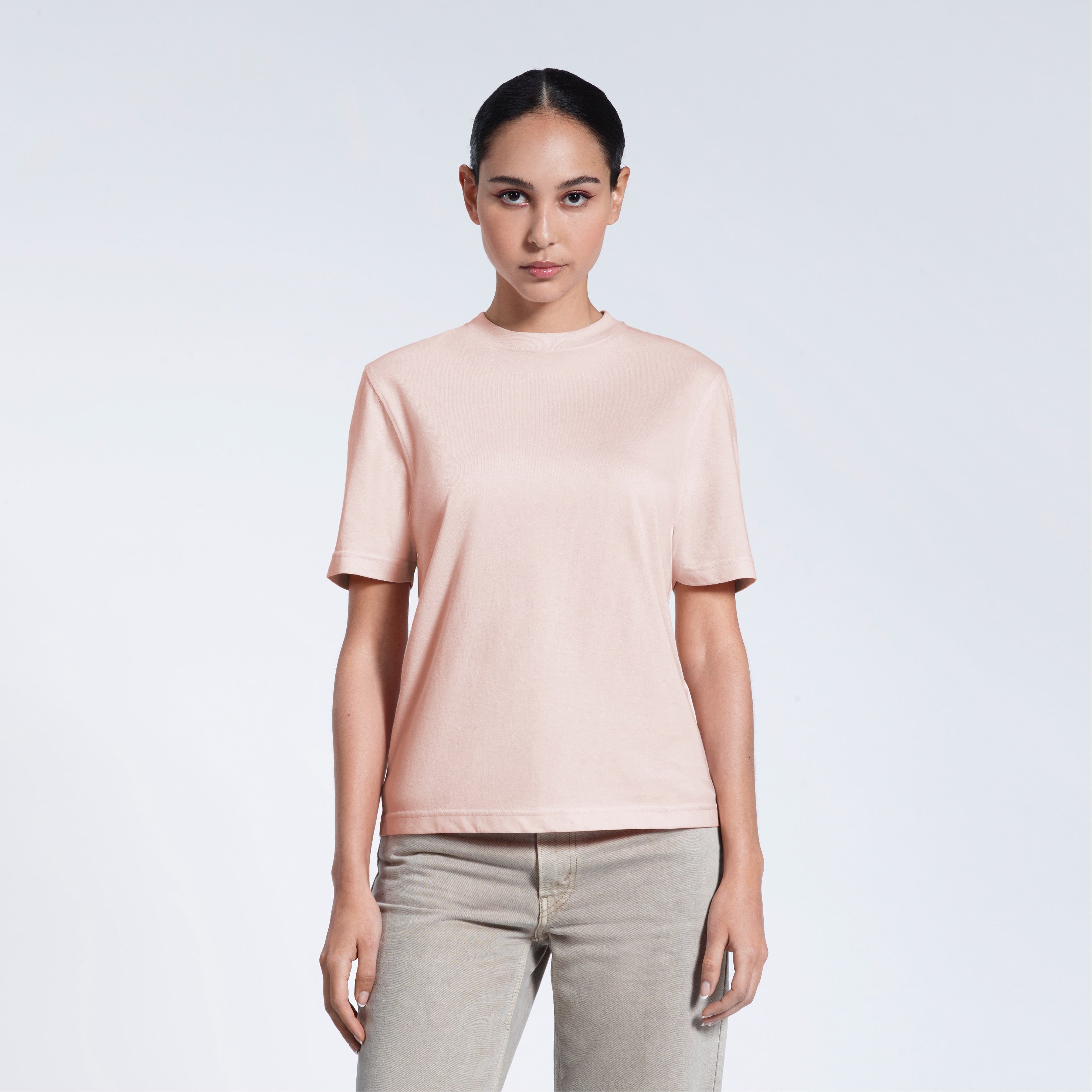 A woman facing front on looking at the camera, modelling a pink short sleeve organic cotton t shirt.
