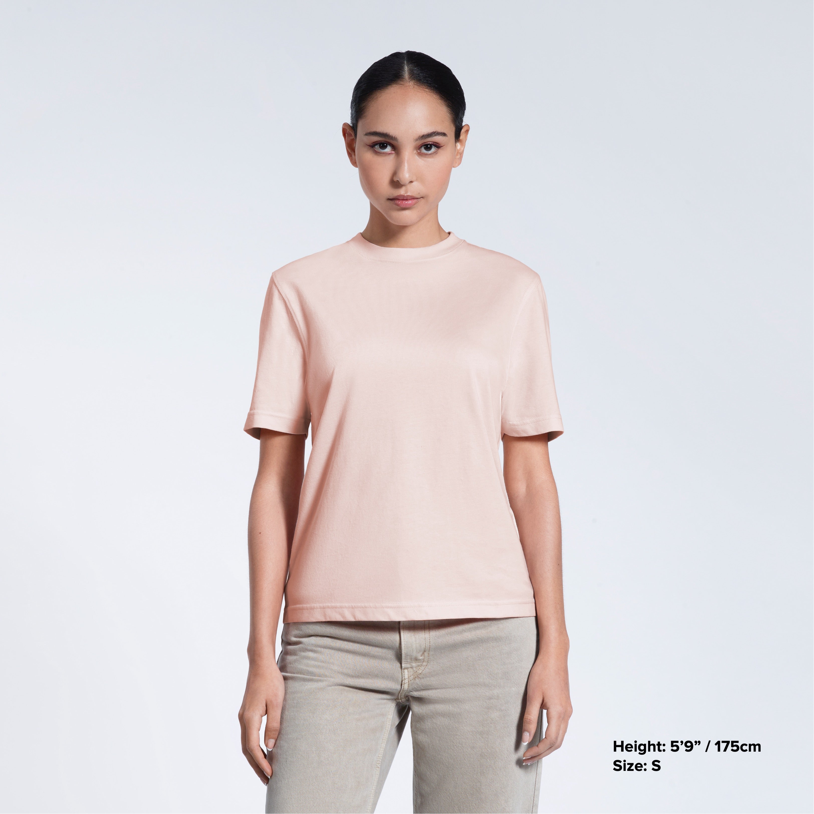 A woman facing front on looking at the camera, modelling a pink short sleeve organic cotton t shirt.