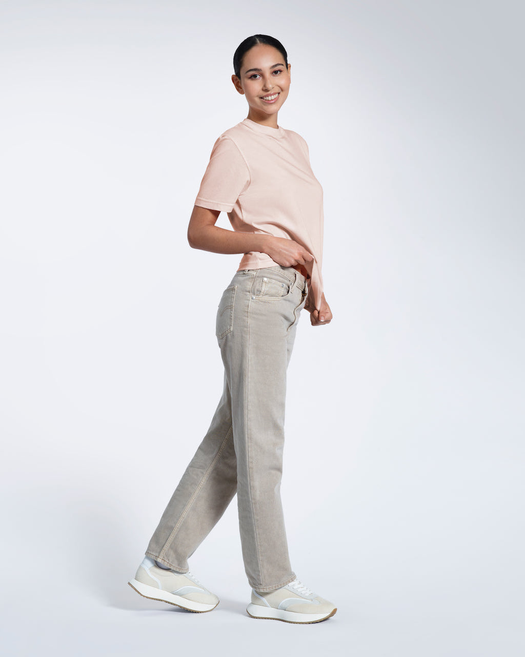 A woman walking and smiling at the camera, modelling a plain pink short sleeve organic cotton t shirt.