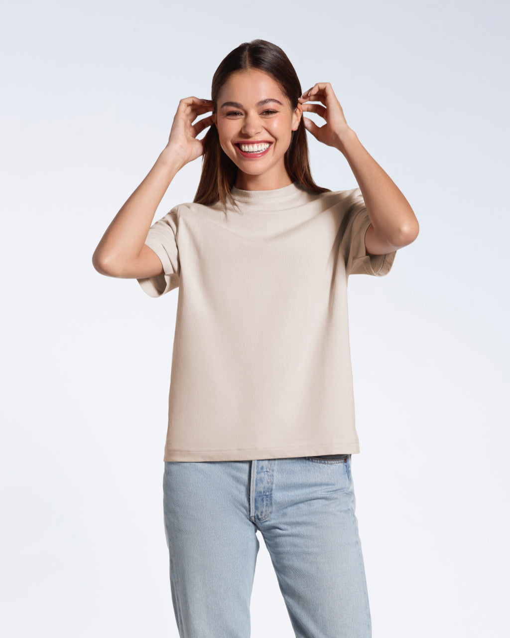 A woman smiling tucking her hair behind her ears, modelling a plain pink short sleeve organic cotton t shirt.