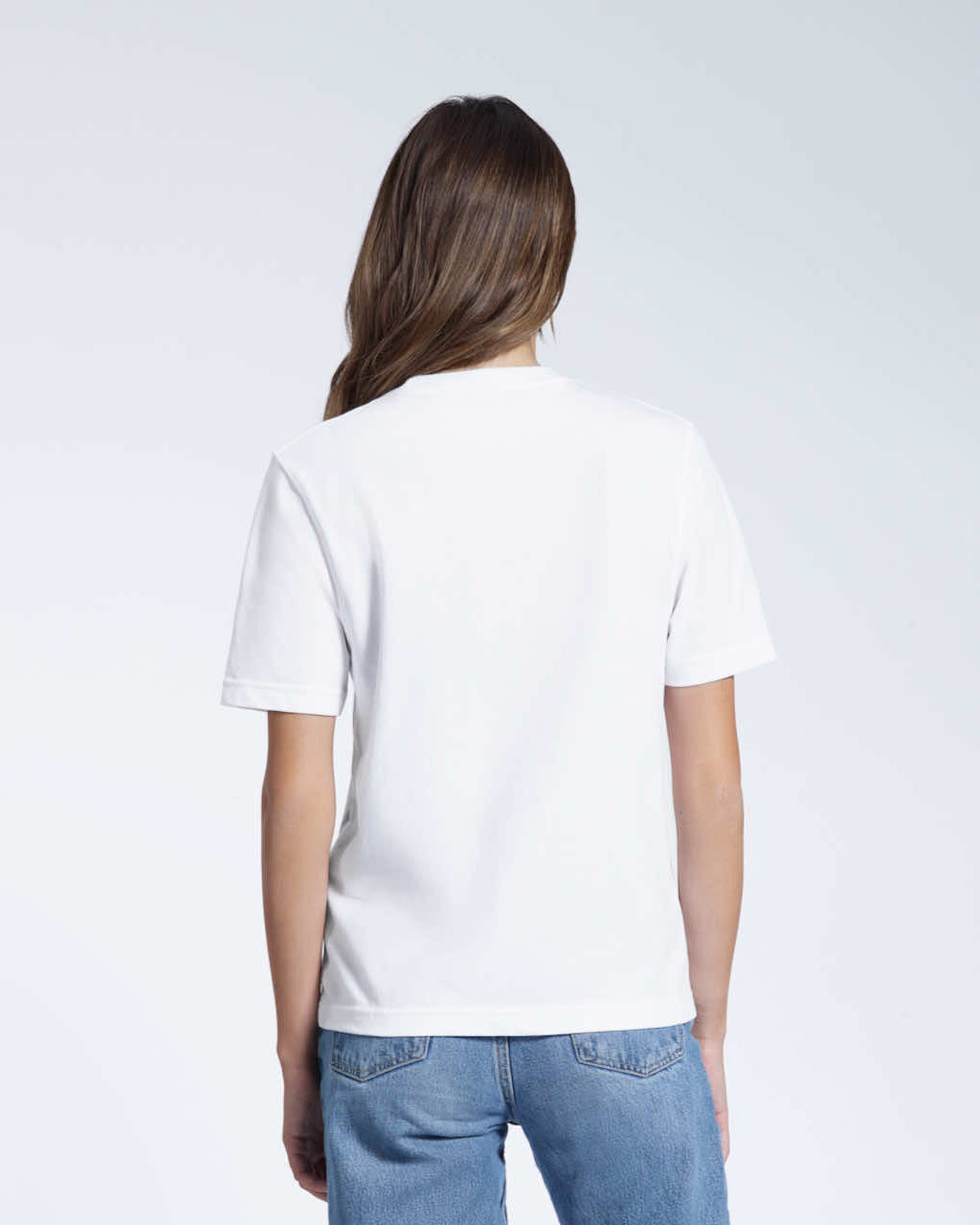 A woman with her back to the camera, modelling a plain white short sleeve organic cotton t shirt.