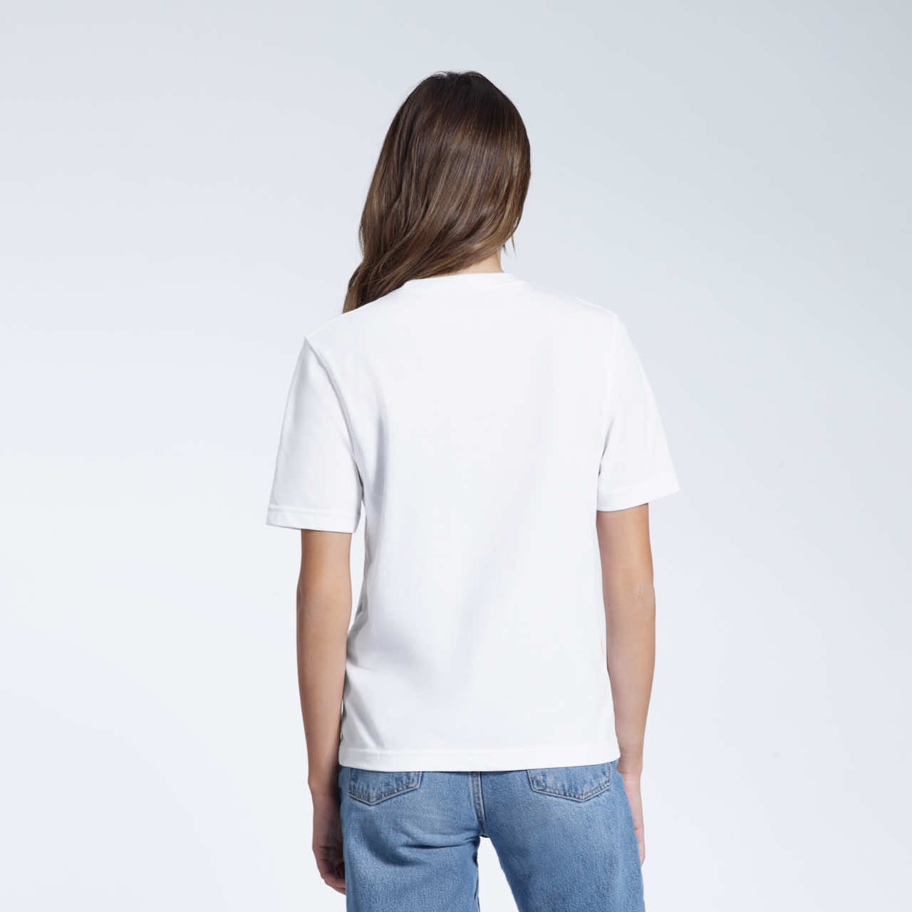 A woman with her back to the camera, modelling a plain white short sleeve organic cotton t shirt.