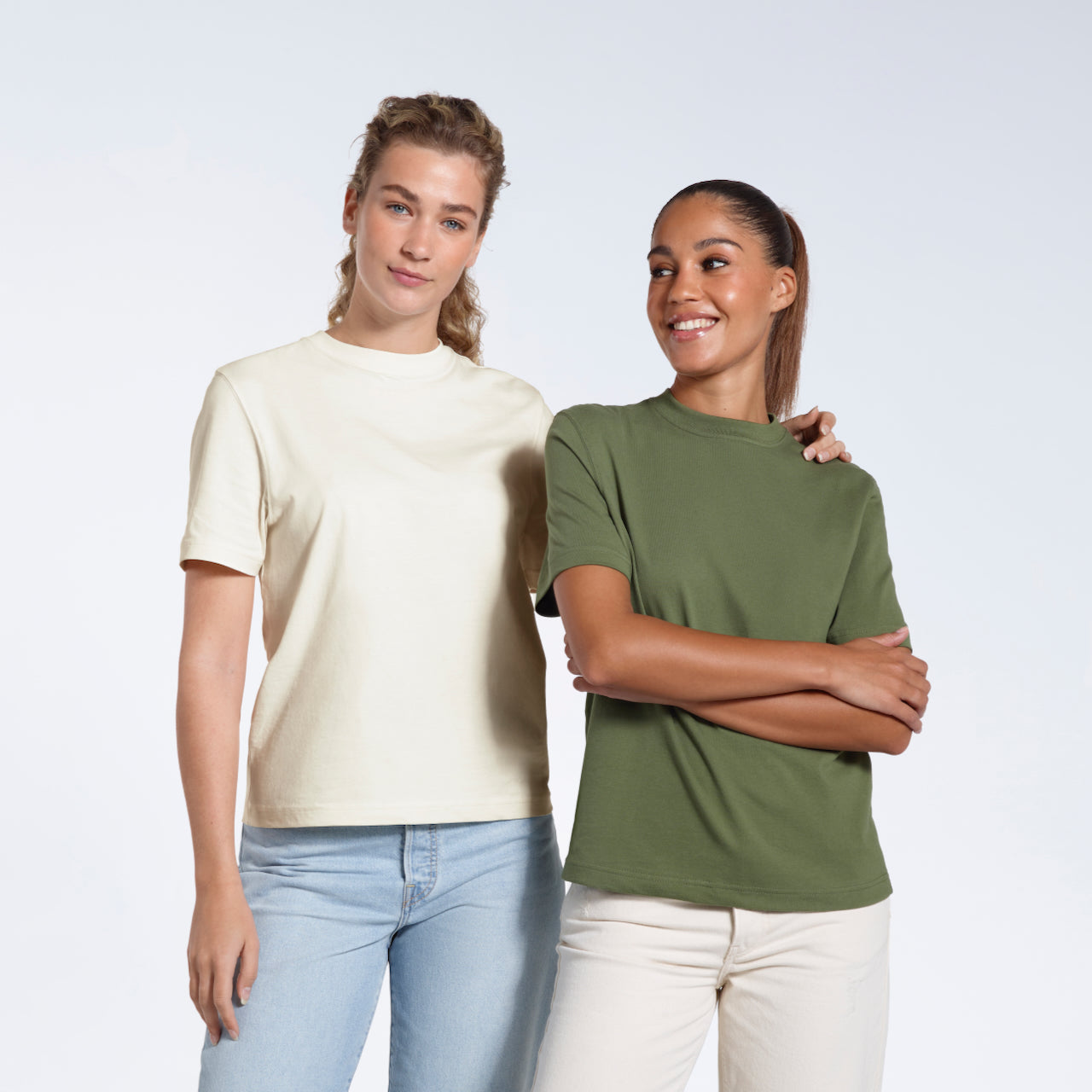 Two women smiling, modelling plain ecru and khaki green organic cotton t shirts.