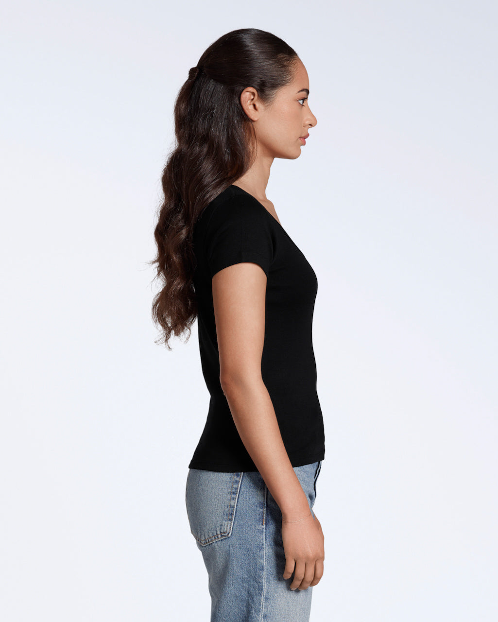 A woman facing side on, with her arms by her side, modelling a plain black, organic cotton scoop neck t shirt.