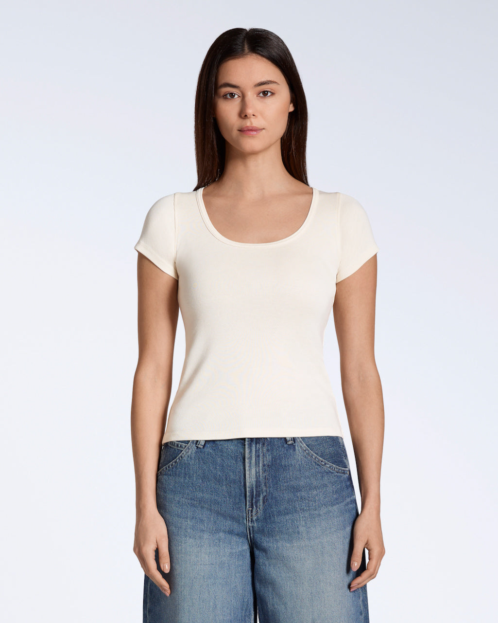 A woman facing front on, looking into the camera with her arms by her side, modelling a plain natural, organic cotton scoop neck t shirt.