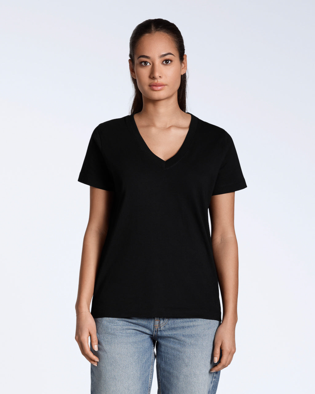 A woman facing front on, looking into the camera with her arms by her side, modelling a plain black, organic cotton v neck t shirt.