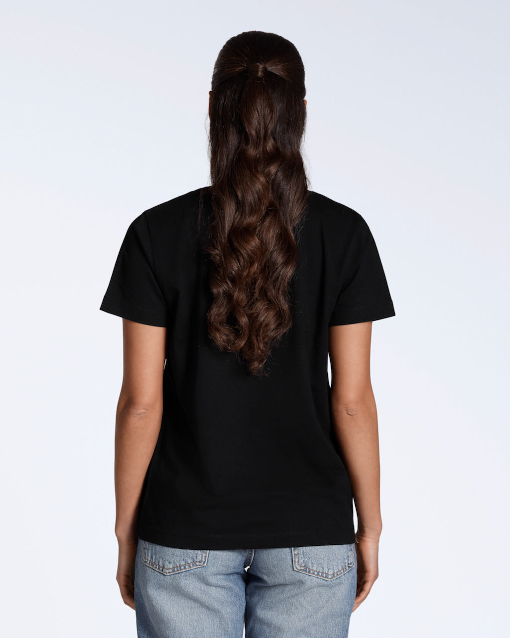 A woman facing away from the camera, modelling a plain black, organic cotton v neck t shirt.
