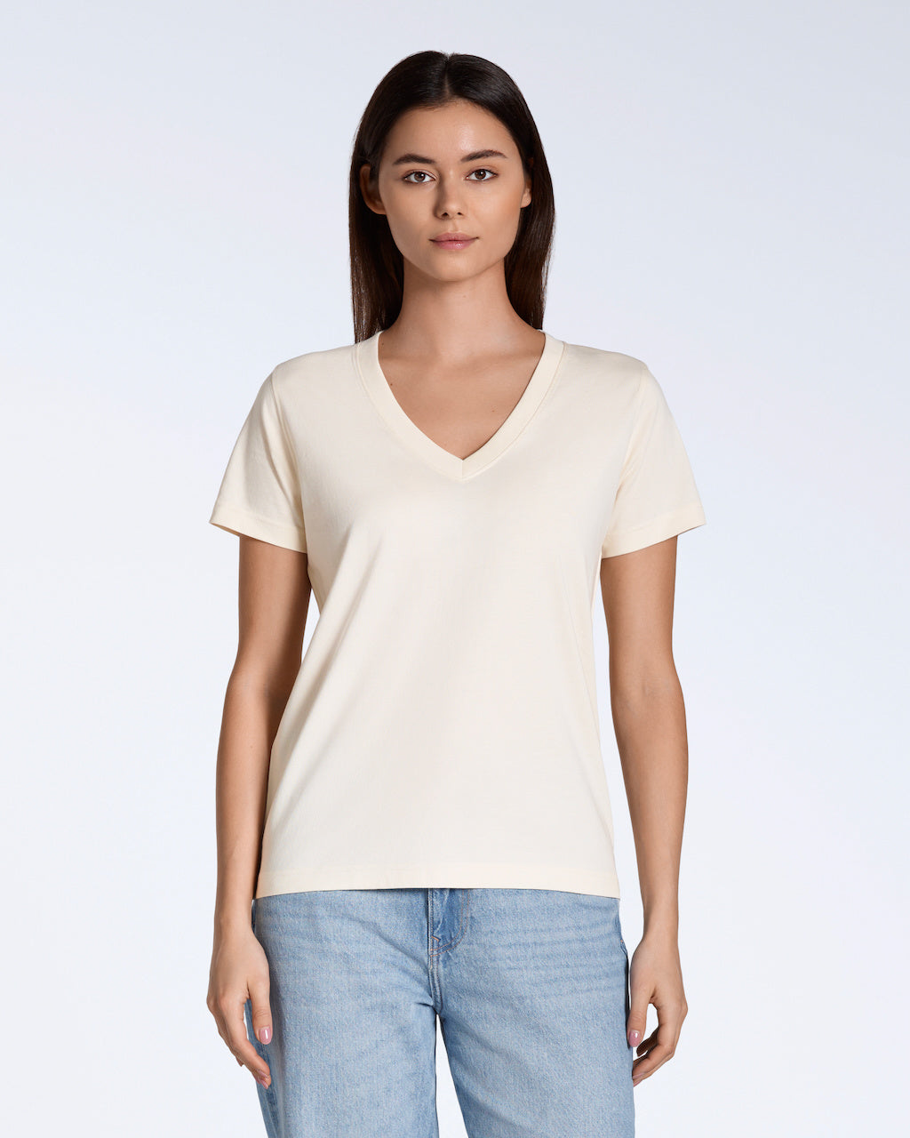 A woman facing front on, looking into the camera with her arms by her side, modelling a plain natural coloured, organic cotton v neck t shirt.