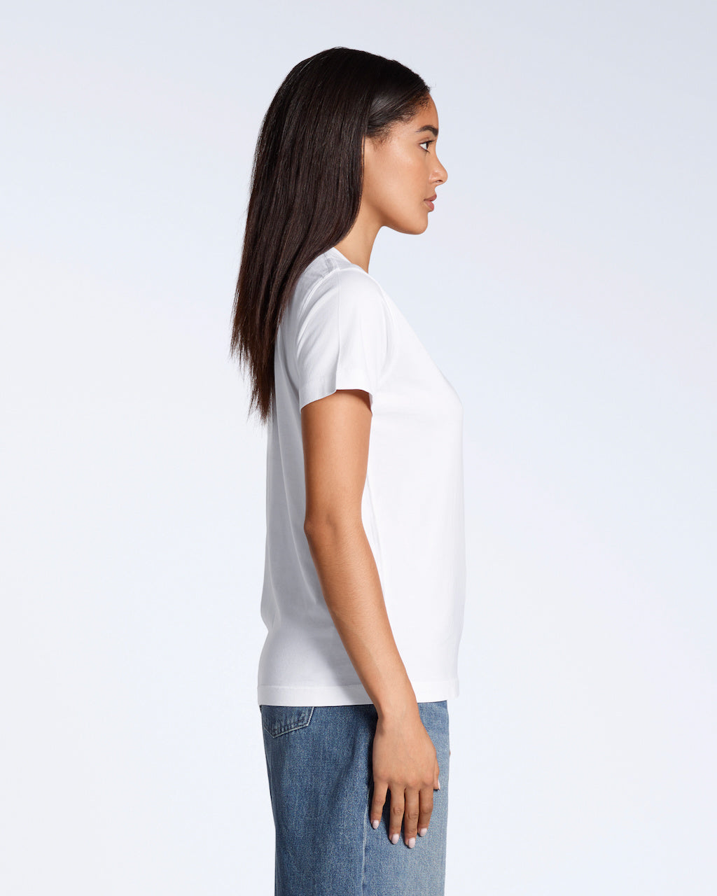 A woman facing side on, with her arms by her side, modelling a plain white, organic cotton v neck t shirt.