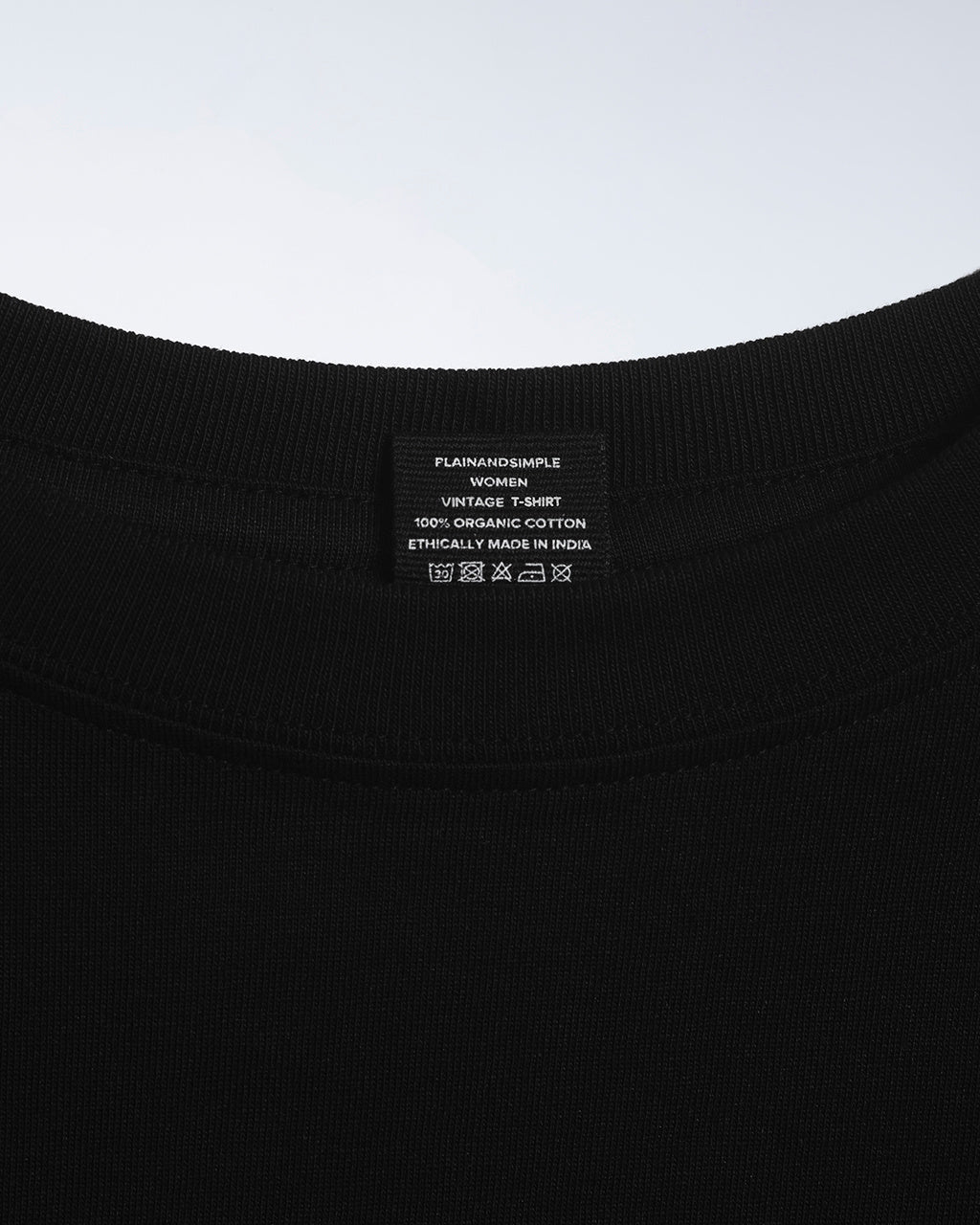 A close up of an neck label in a women's black short sleeve crew neck organic cotton t shirt.