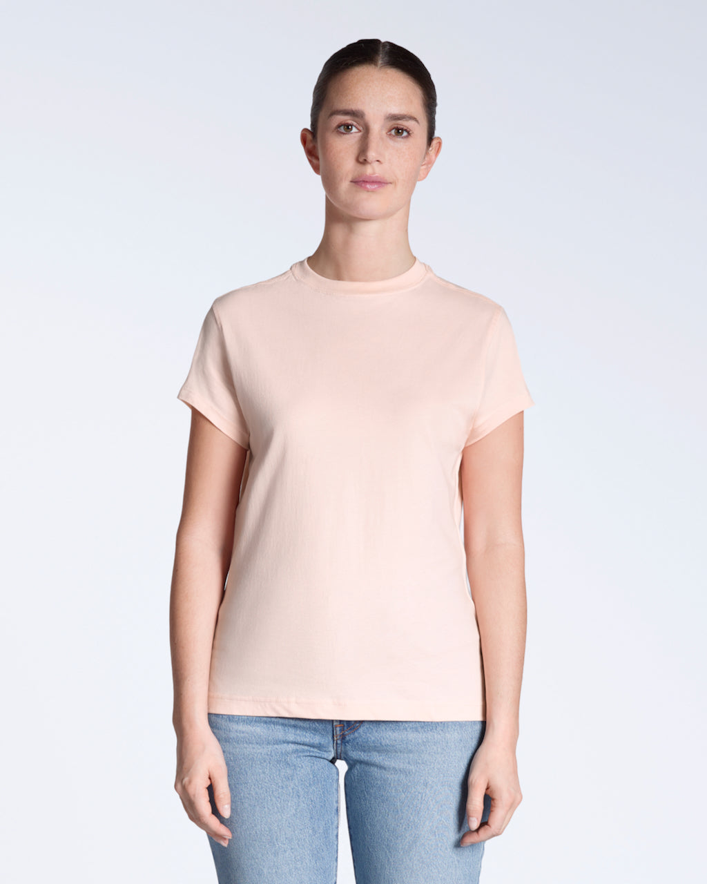 A woman facing front on looking into the camera, modelling a plain pink, organic cotton t shirt.
