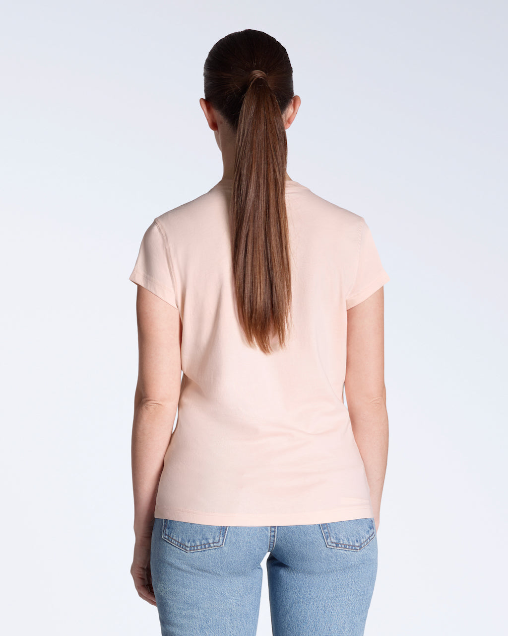 A woman facing away from the camera, modelling a plain pink, short sleeve organic cotton t shirt.