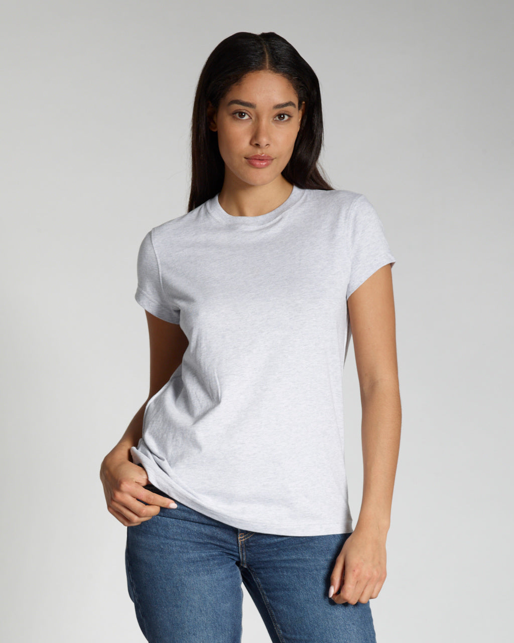 A woman looking into the camera, modelling a plain grey, short sleeve organic cotton t shirt.
