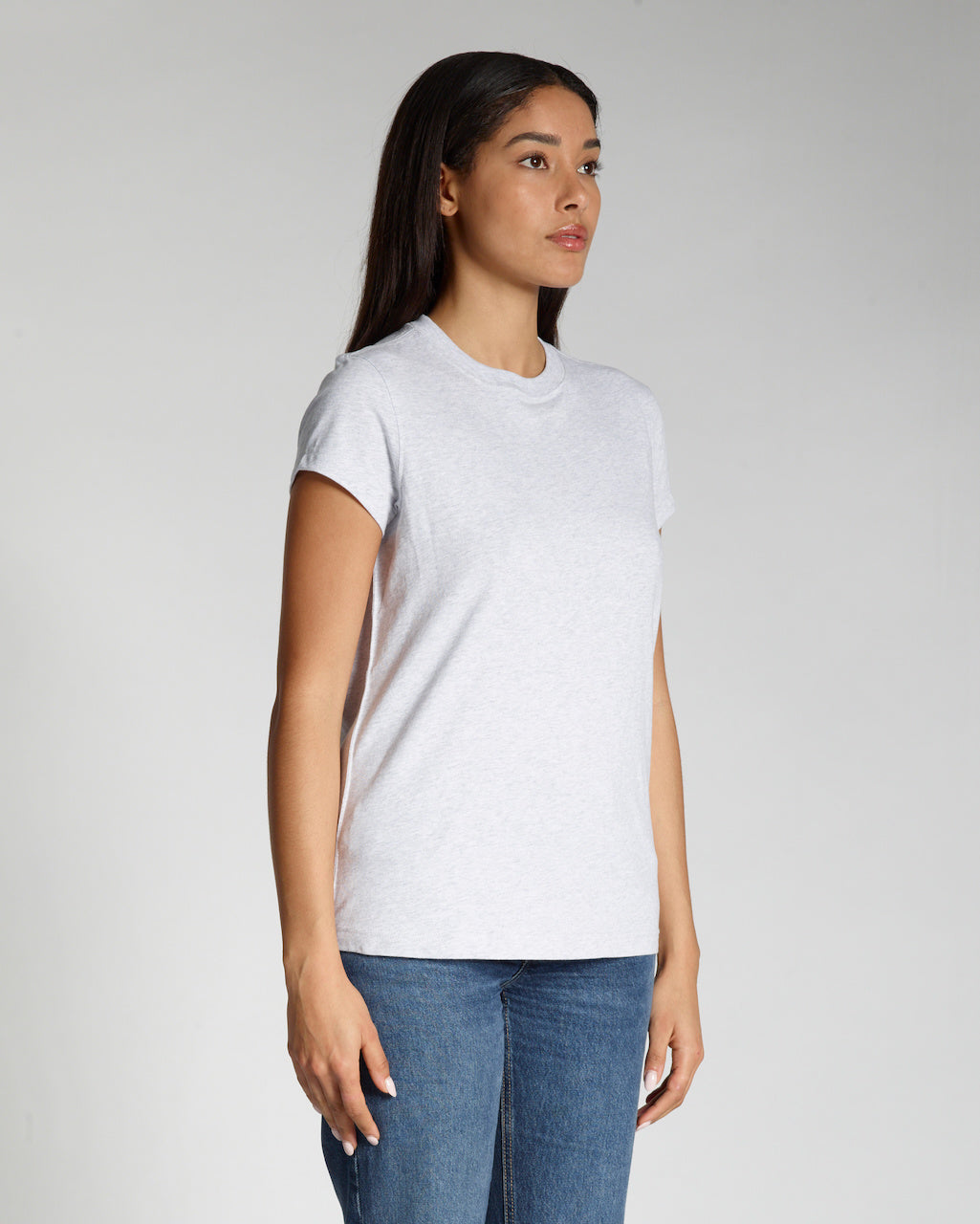 A woman at an angle with her arms by her sides, modelling a plain grey, short sleeve organic cotton t shirt.
