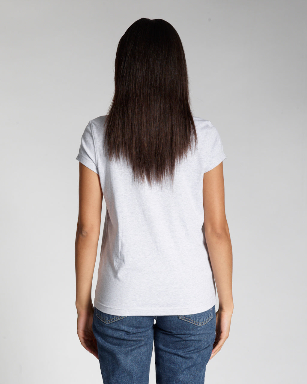 A woman facing away from the camera, modelling a plain grey, short sleeve organic cotton t shirt.