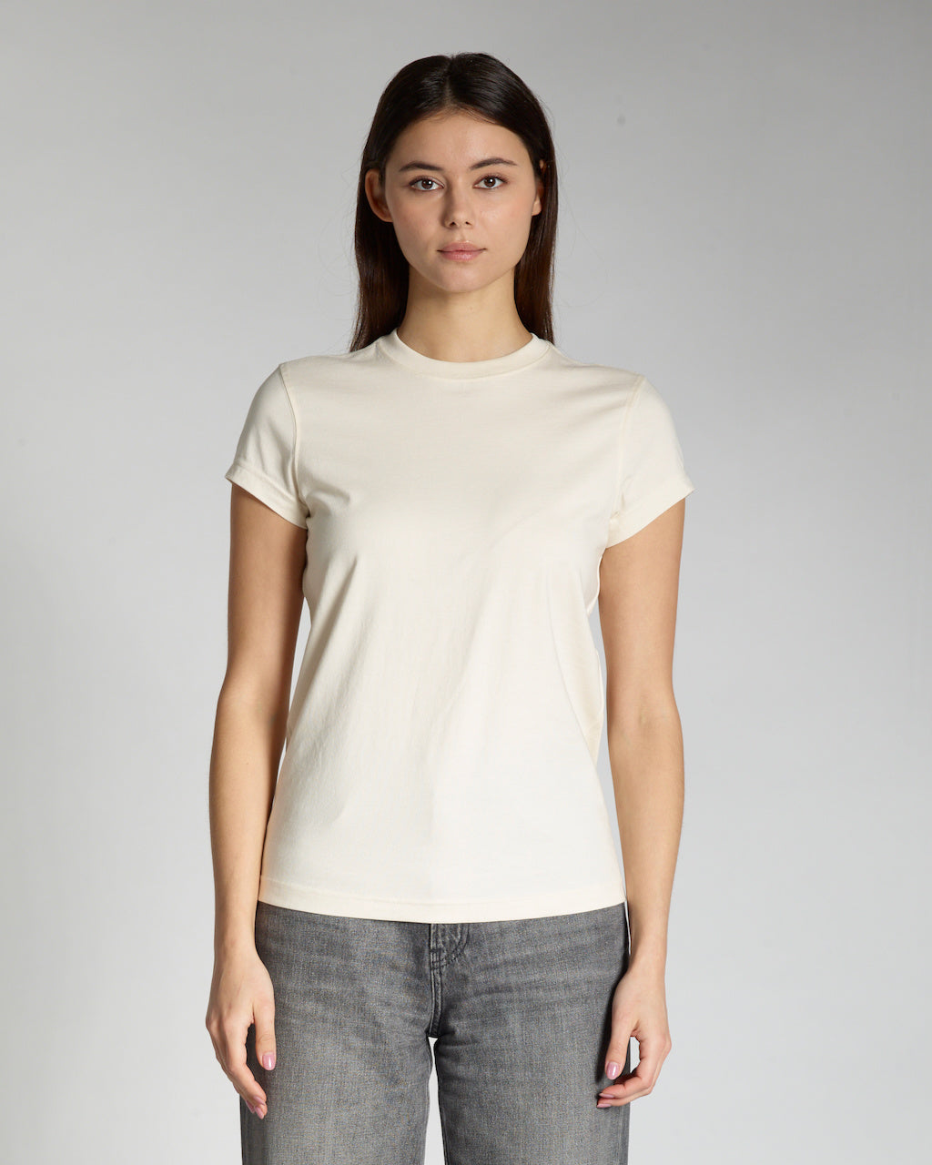 A woman facing front on, modelling a plain natural coloured, short sleeve organic cotton t shirt.