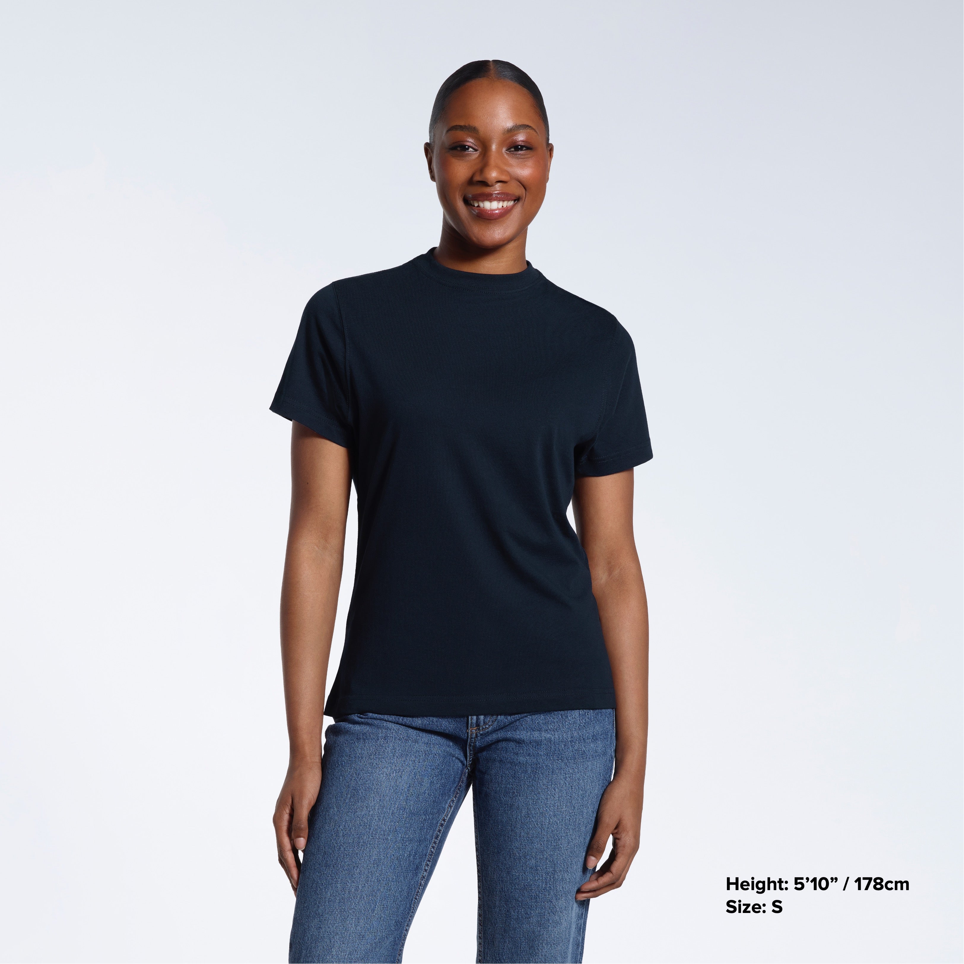 A woman facing front on smiling into the camera, modelling a plain navy short sleeve organic cotton t shirt.