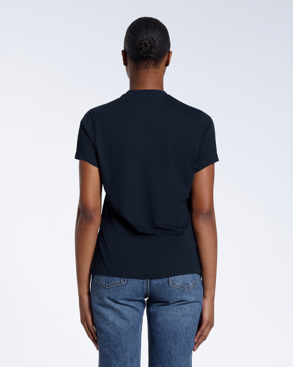 A woman with her back to the camera, modelling a plain navy short sleeve organic cotton t shirt.