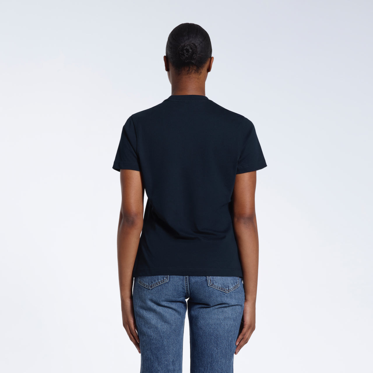A woman with her back to the camera, modelling a plain navy short sleeve organic cotton t shirt.