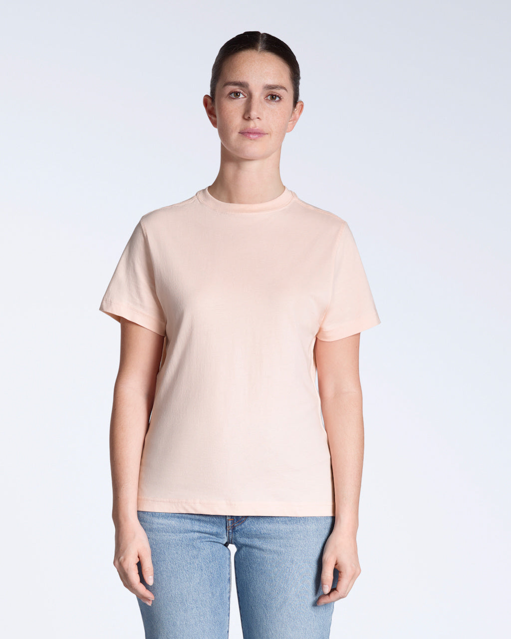 A woman facing front on, modelling a plain pink, short sleeve organic cotton t shirt.