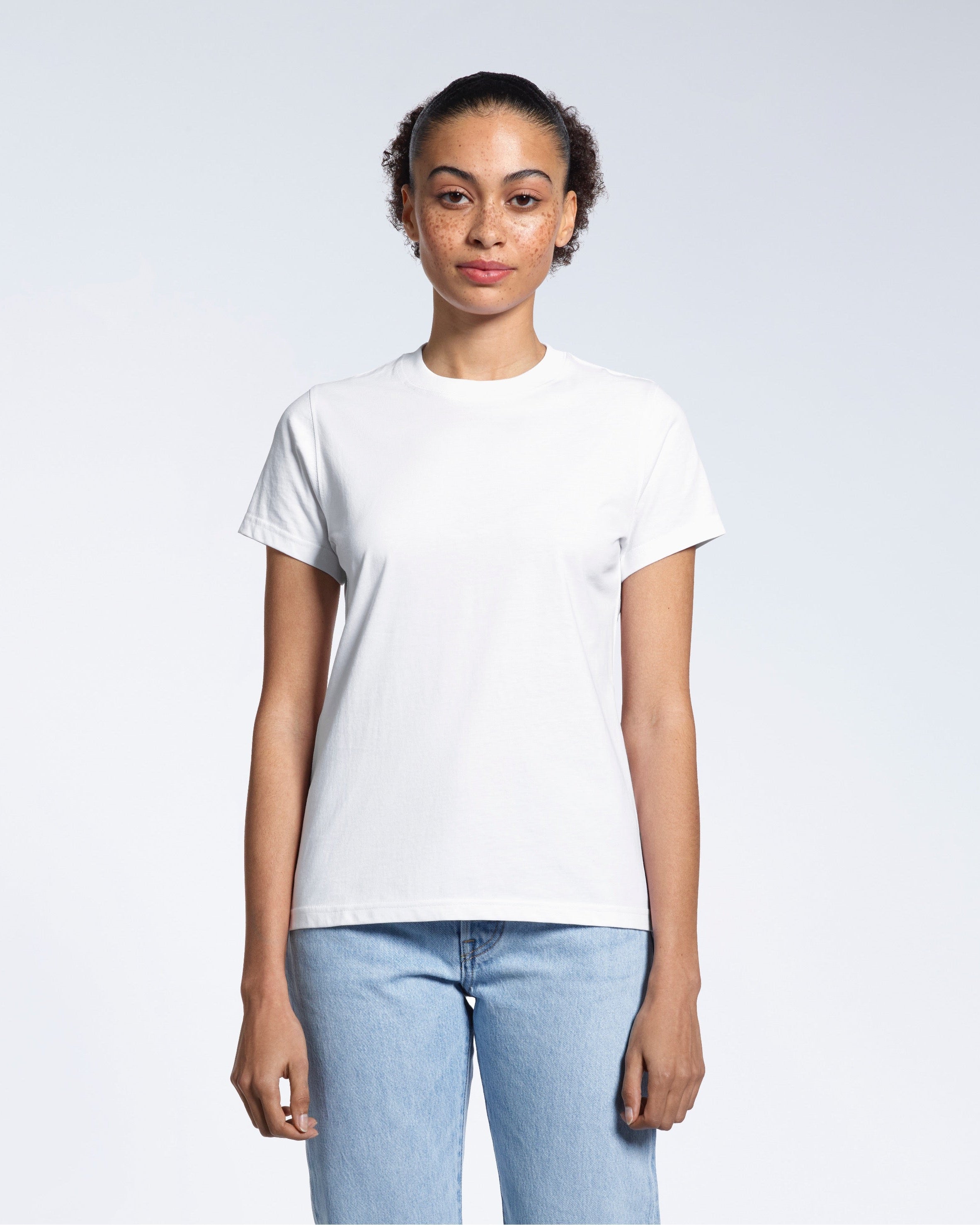 A woman facing front on looking into the camera, modelling a plain white short sleeve organic cotton t shirt.