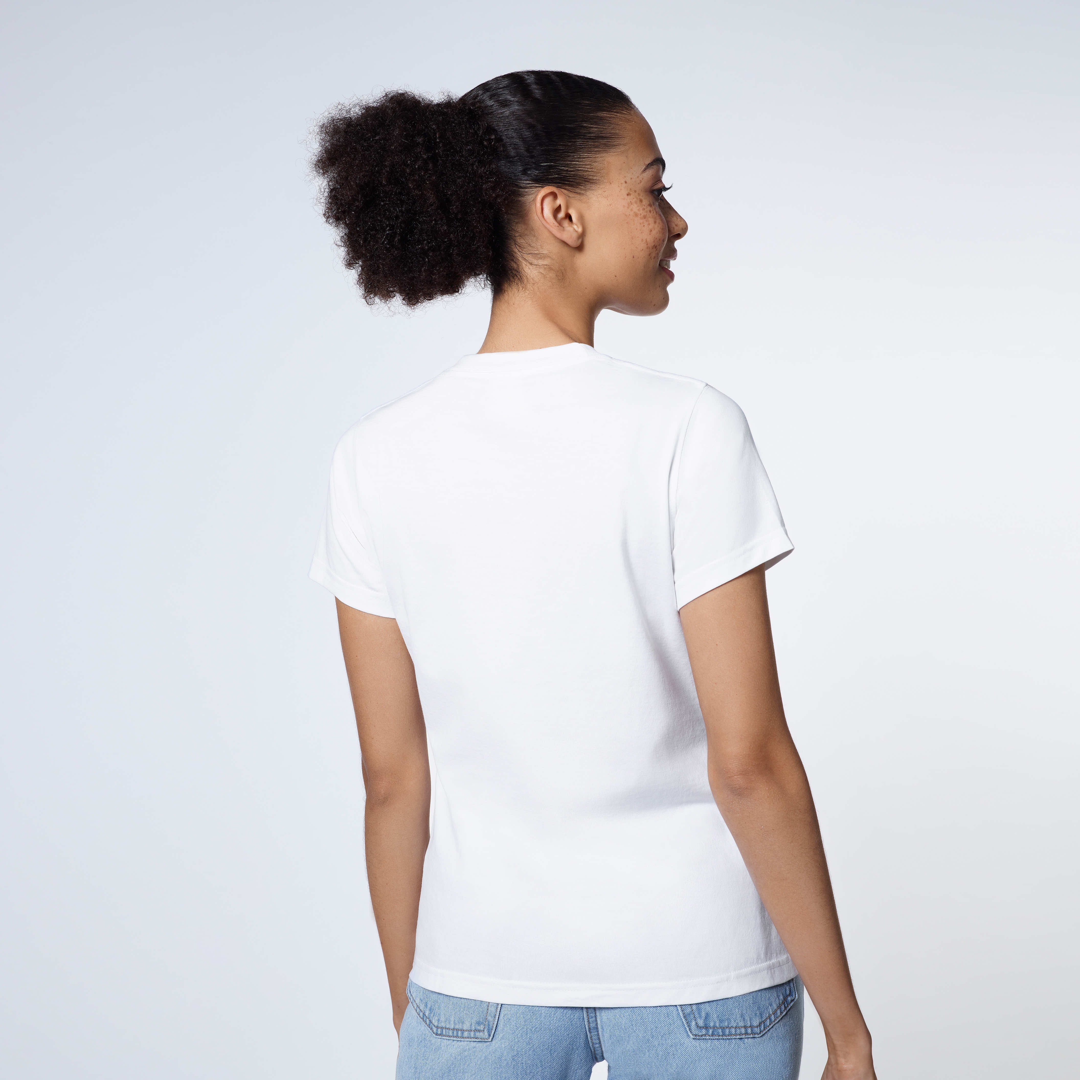 A woman facing away from the camera modelling a plain white short sleeve organic cotton t shirt.