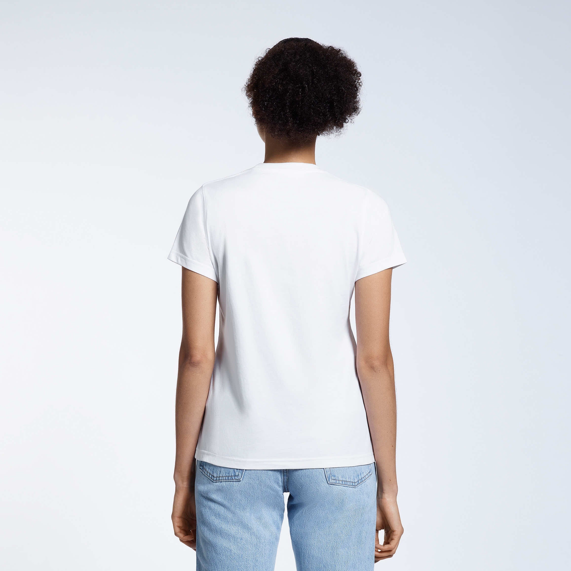 A woman with her back to the camera, modelling a plain white short sleeve organic cotton t shirt.