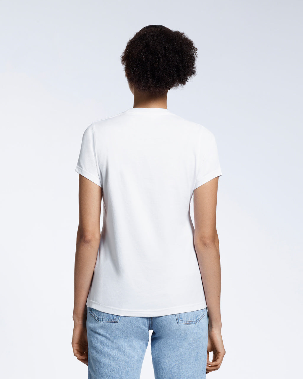 A woman with her back to the camera, modelling a plain white short sleeve organic cotton t shirt.
