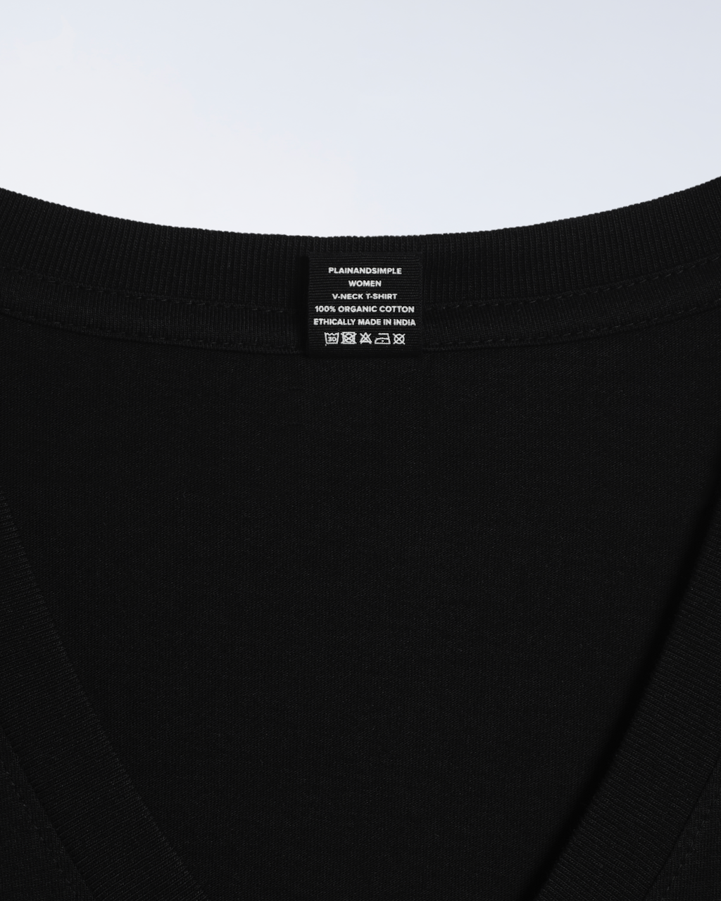 A close up of the neck label in a black, v neck, organic cotton t shirt.
