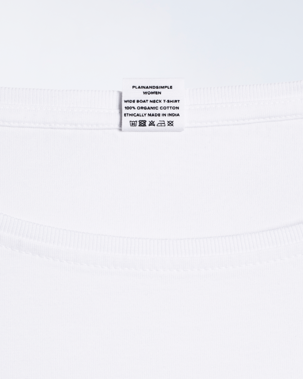A close up of the neck label in a black, wide boat neck, organic cotton t shirt.