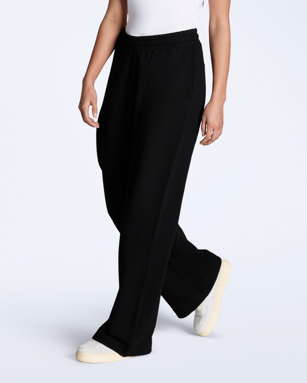 A woman modelling a pair of black, organic cotton, wide leg joggers.
