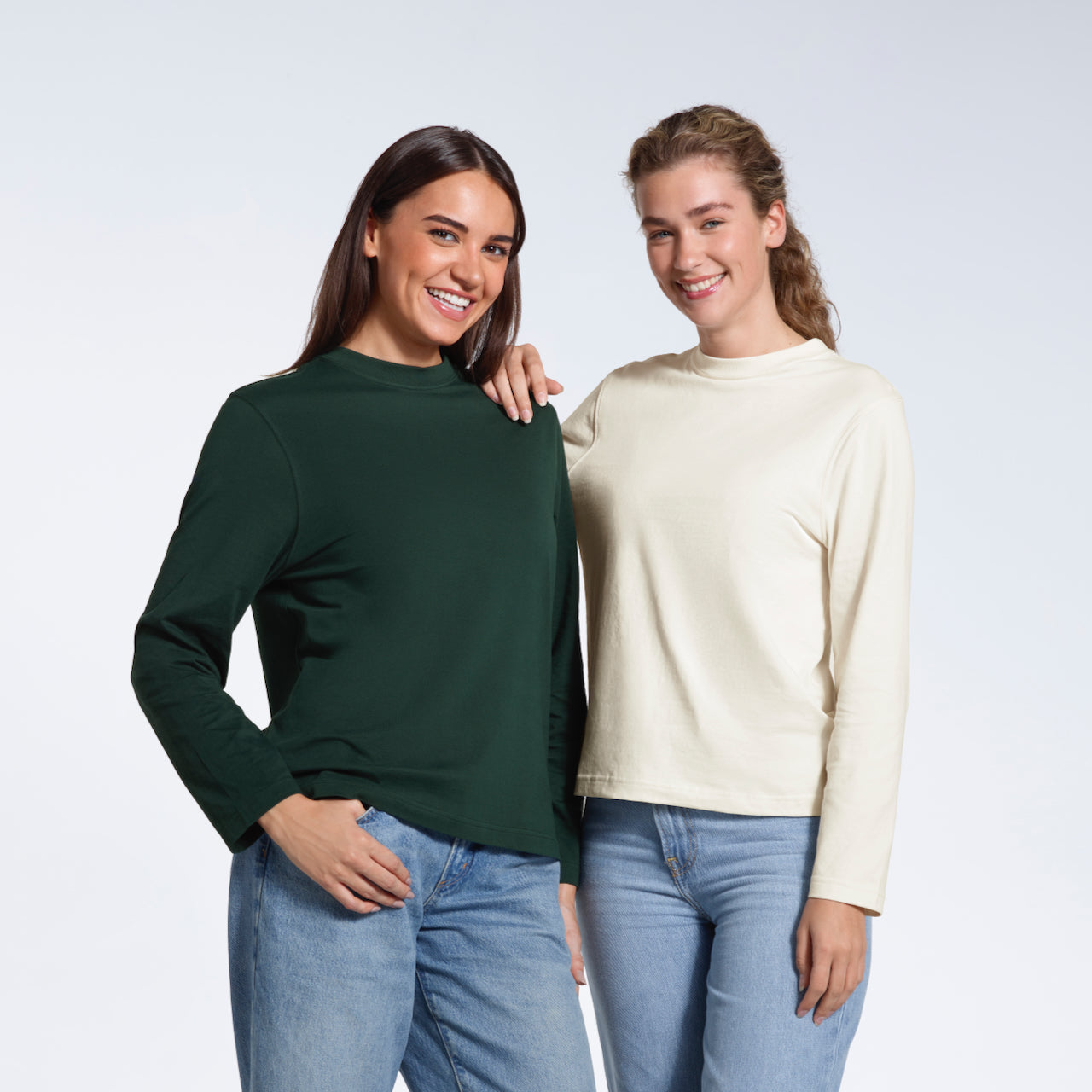 Two women smiling at the camera, modelling plain green and ecru long sleeve organic cotton t shirts.