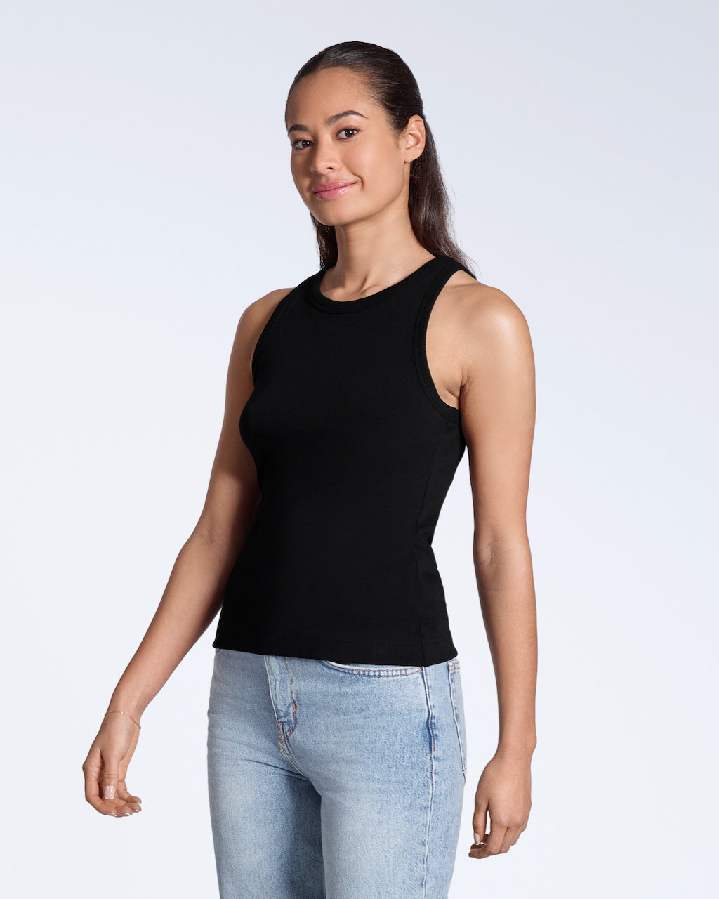 A woman at an angle smiling into the camera, modelling a plain black, organic cotton tank top.