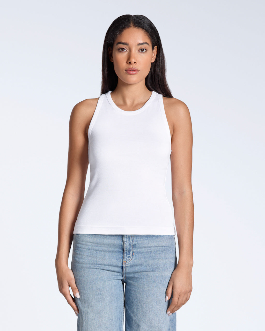 A woman facing front on, modelling a plain white, organic cotton tank top.