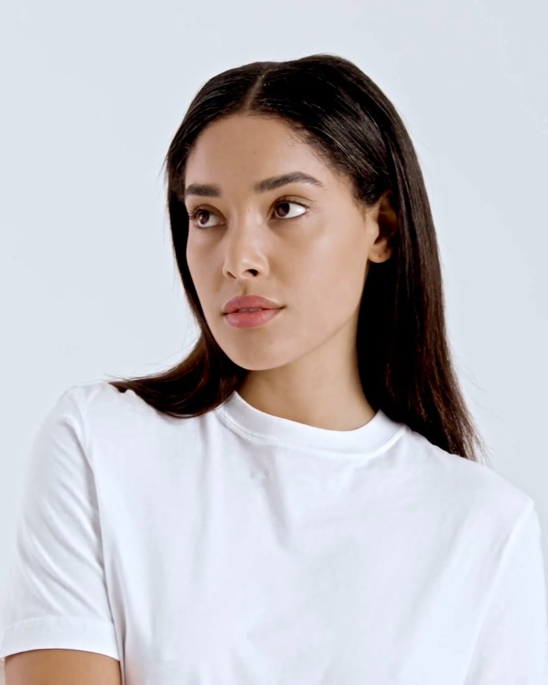 A compilation of short video clips of a woman modelling a plain white, organic cotton t shirt with a pair of jeans.
