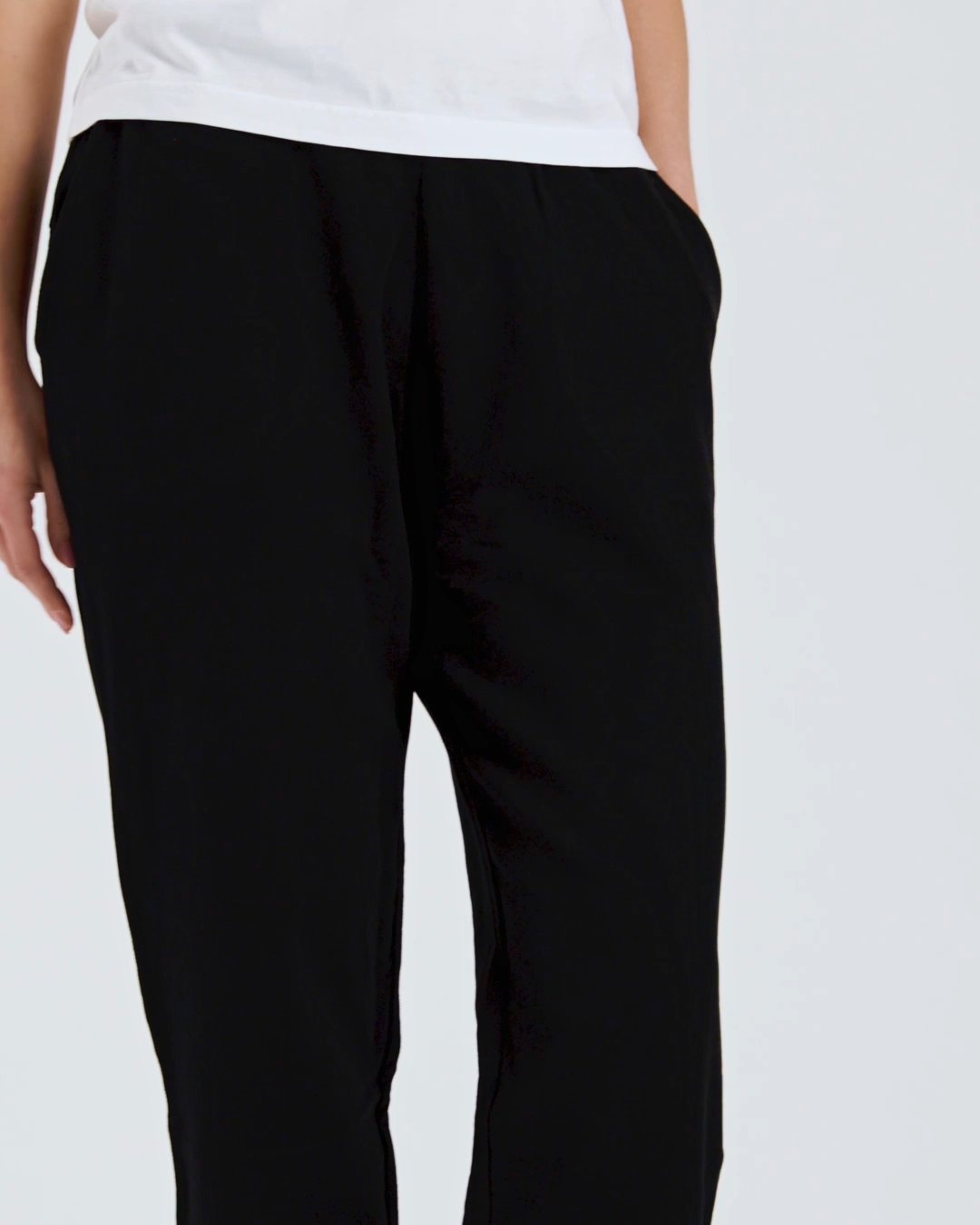 A compilation of short video clips of a woman modelling plain black, organic cotton joggers with a white t shirt.