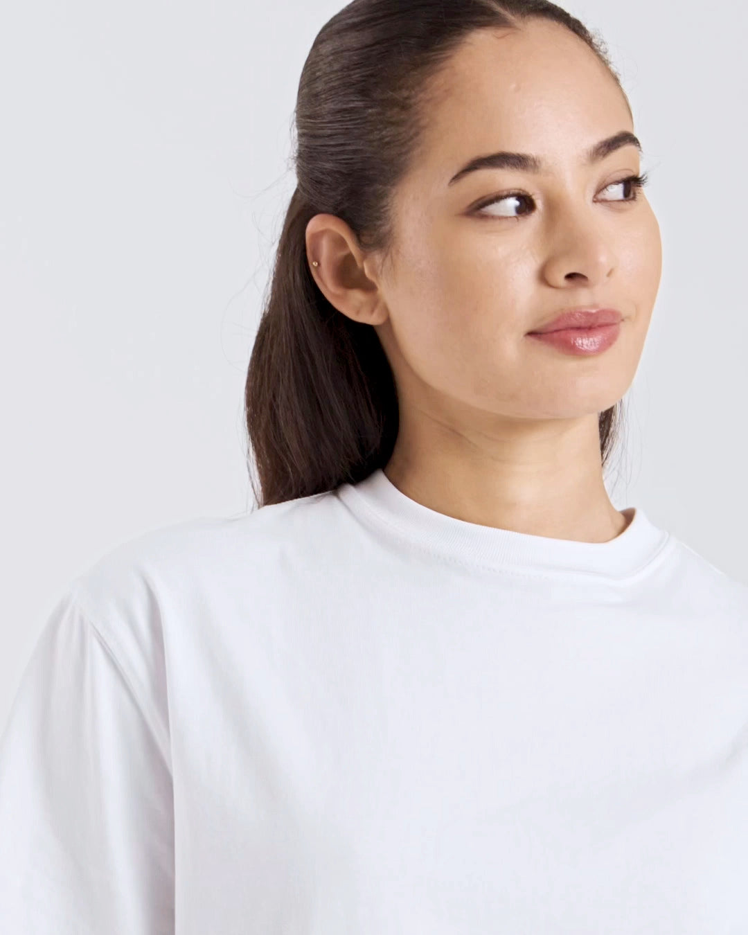 A compilation of short video clips, of a woman modelling a plain white, boxy, organic cotton t shirt with a pair of jeans.