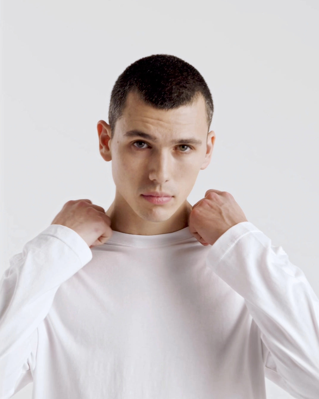 A compilation of short video clips of a man modelling a plain white, organic cotton long sleeve t shirt, with a pair of jeans.
