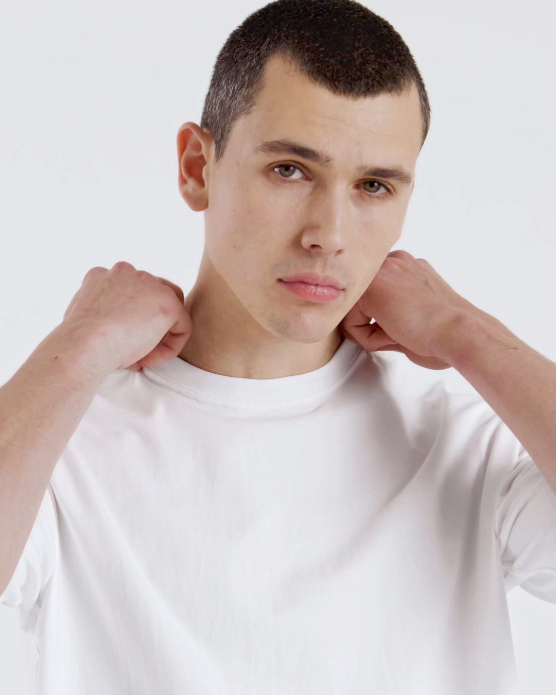A compilation of short video clips of a man modelling a plain white, oversized organic cotton t shirt with a pair of black jeans.